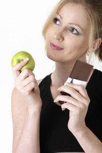 woman deciding whether to eat apple or chocolate