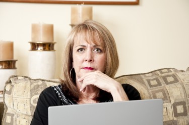 Mature woman sitting on her couch using her laptop computer