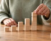 Person arranging wooden blocks into ascending columns to represent building lasting habits