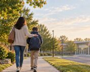 Parent supporting a child as they walk toward school on a quiet morning