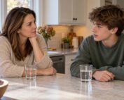 Mother listening to her teenage son during a quiet conversation at their kitchen counter.